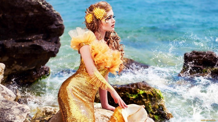 Woman in golden dress with seashell by the sea