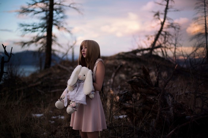 Girl holding a stuffed bunny in a desolate forest