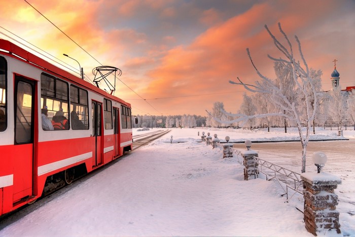 Red tram in a snowy winter landscape at sunset