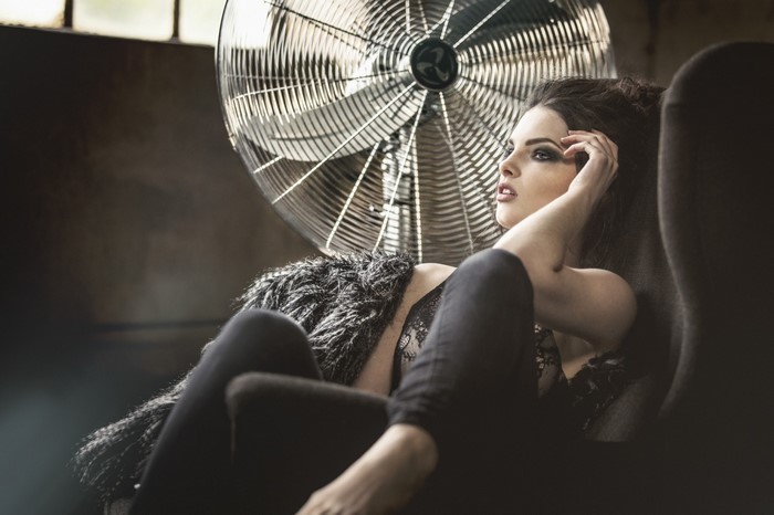 Woman in black sitting in front of a fan