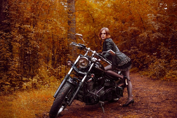 Woman posing on a motorcycle in autumn forest