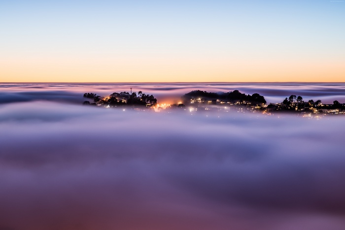 Town on a hill above fog at sunset