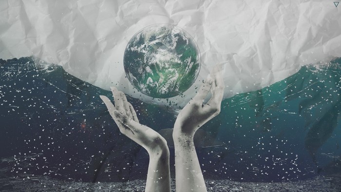 Hands holding the Earth above waves and crumpled paper