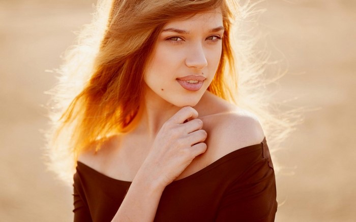 Woman with long auburn hair and mole on face