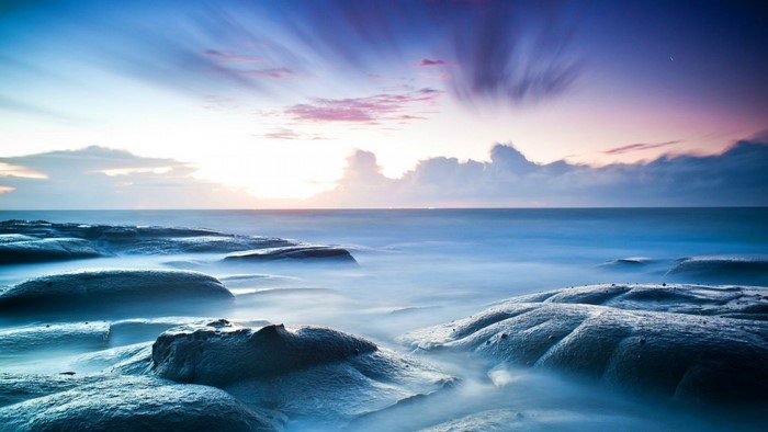 Ocean waves crashing on rocky shore at sunset