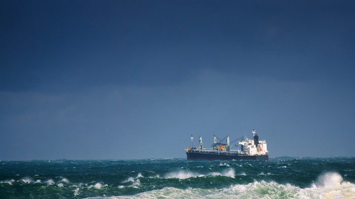 Cargo ship sailing on rough seas under a dark sky