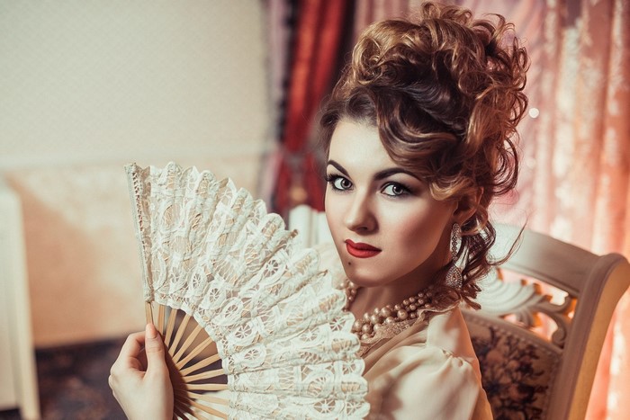 Woman in vintage dress holding a fan
