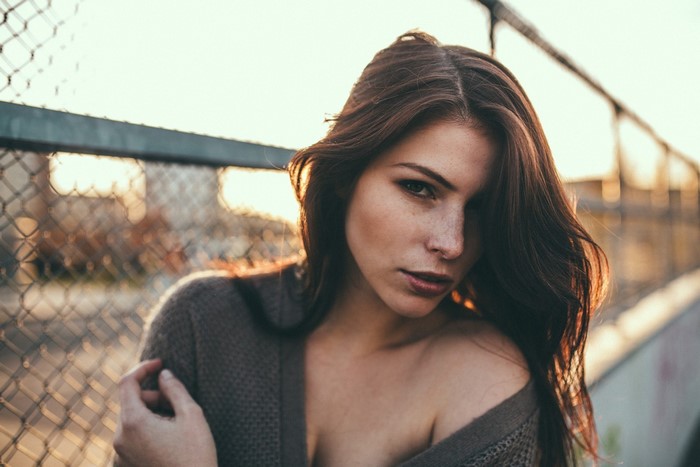 Woman with freckles and brown hair near a fence