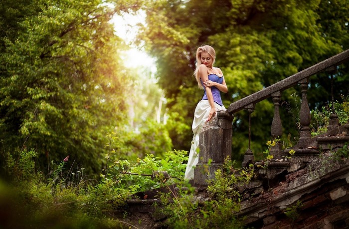 Woman in corset and skirt on stone stairs in forest