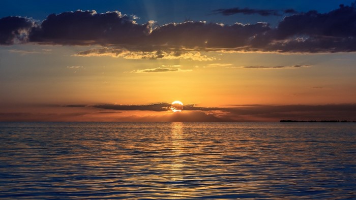 Sunset over the ocean with clouds and sun rays