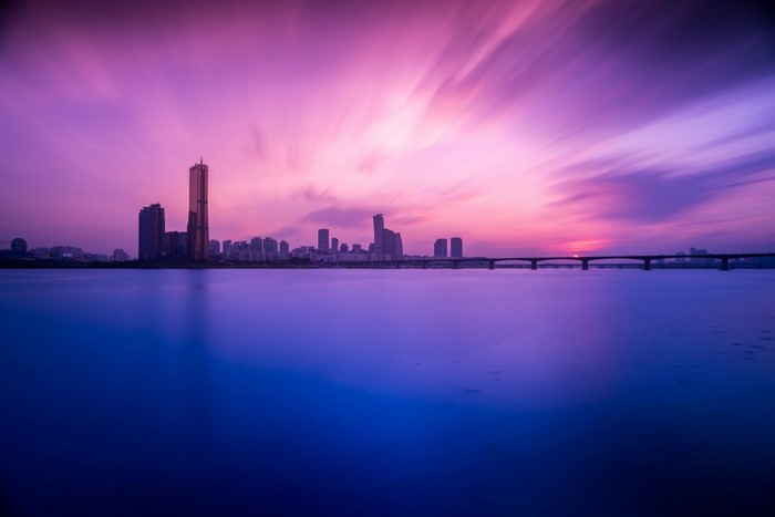 Cityscape with bridge over water at sunset