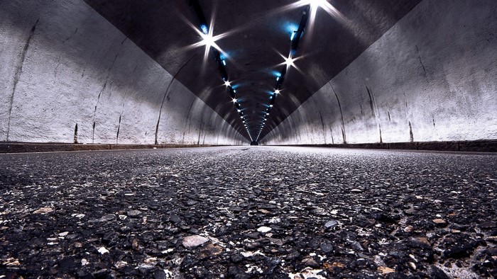 Empty tunnel with lights and asphalt road