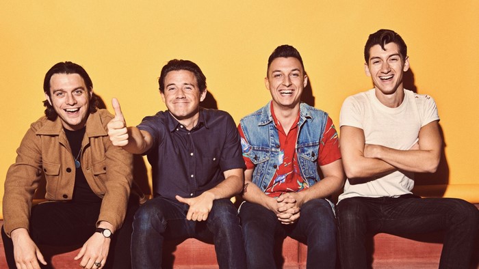 Arctic Monkeys band members posing against a yellow background