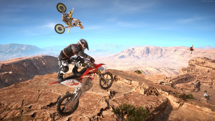 Motocross riders performing stunts in a desert landscape
