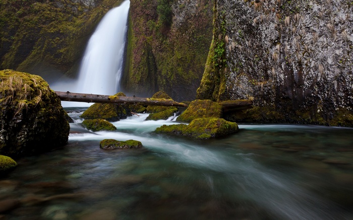 Waterfall flowing over moss-covered rocks into a stream
