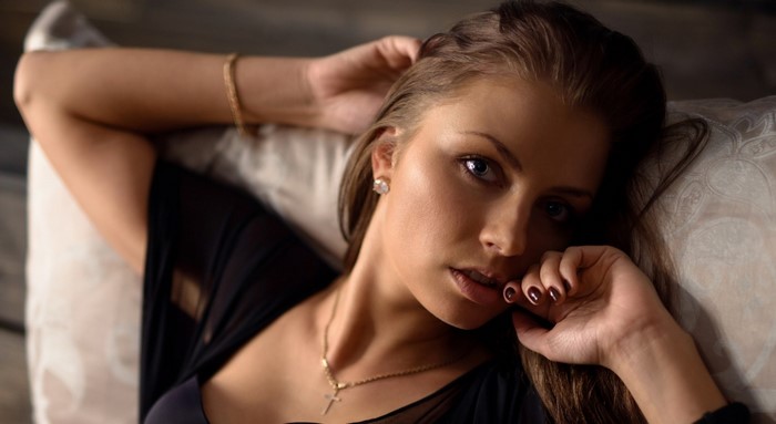 Woman with long brown hair wearing a black top and necklace