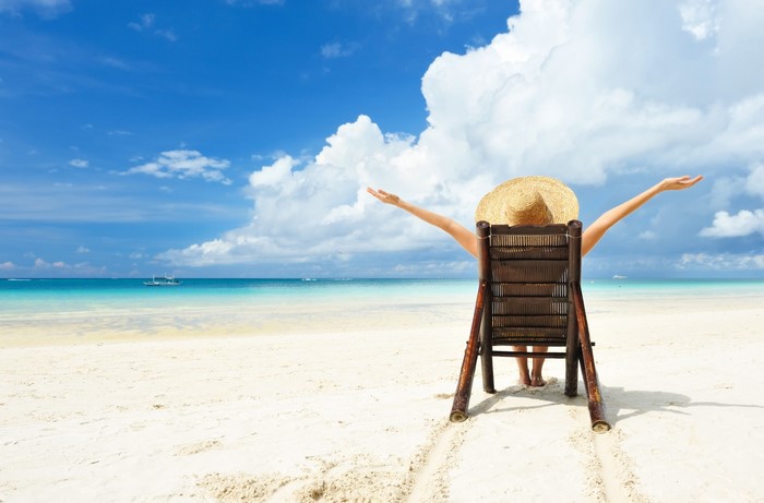 Woman in straw hat relaxing on beach chair by the sea