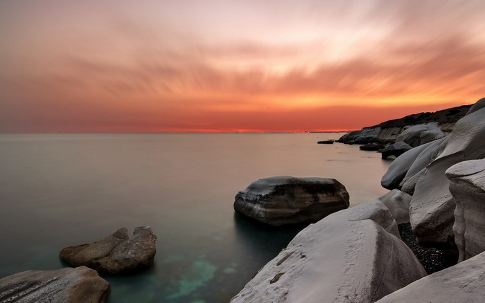 Sunset over the sea with rocks on the shore