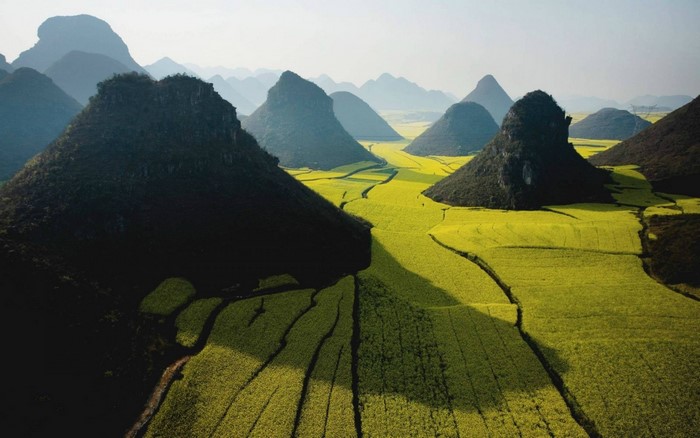 Karst mountains with yellow rapeseed fields in sunlight