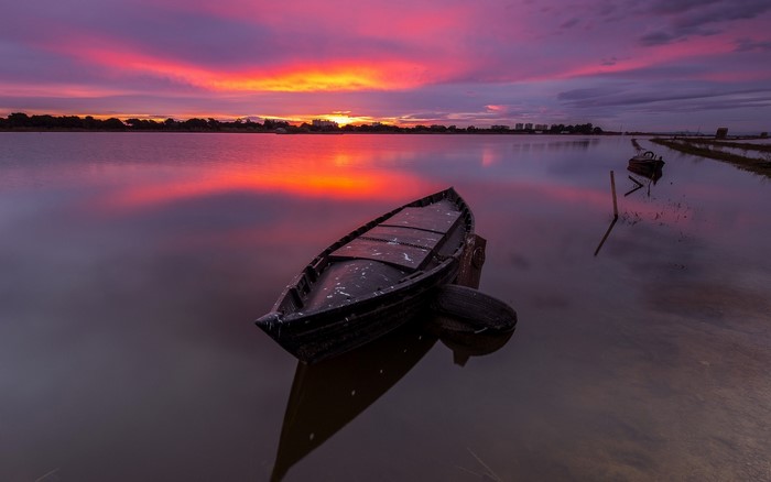 Boat on water during sunset with colorful sky