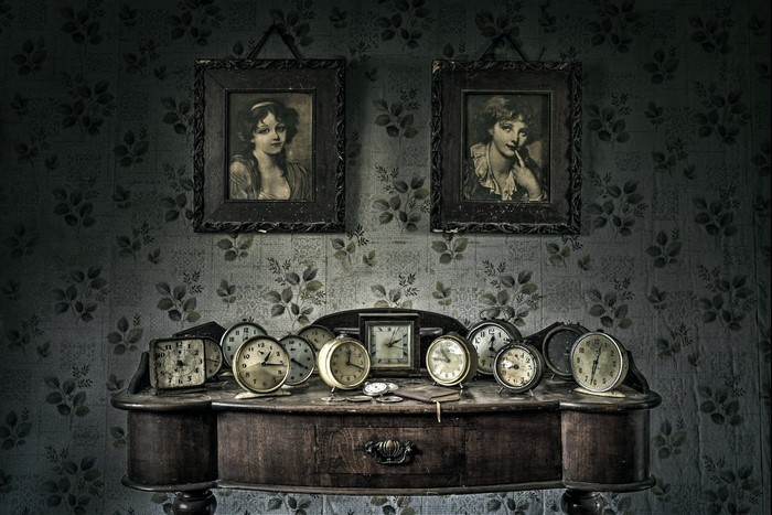Vintage portraits and numerous clocks on a wooden dresser