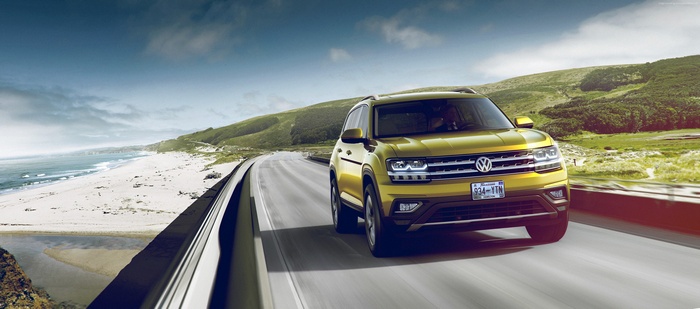 Yellow Volkswagen Atlas driving on coastal highway