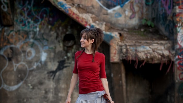 Lindsey Stirling with a violin in front of graffiti