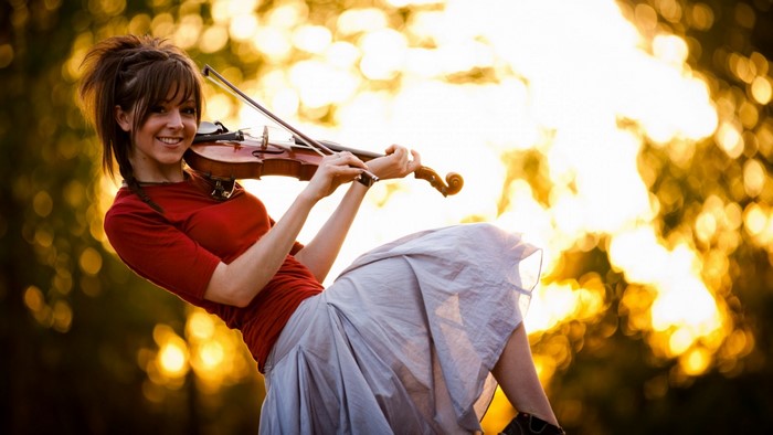 Woman playing violin outdoors with bokeh background