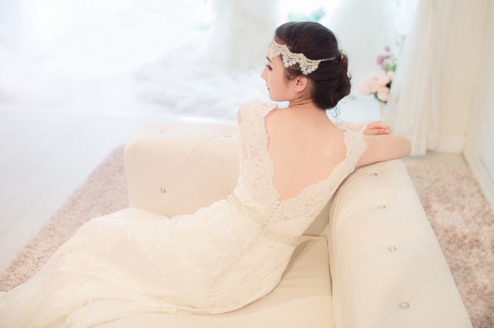 Woman in a white lace wedding dress sitting on a couch