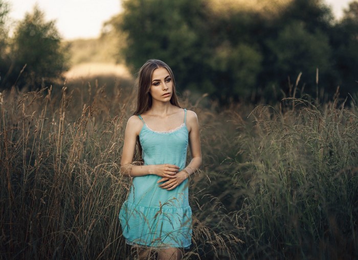 Woman in blue dress standing in tall grass