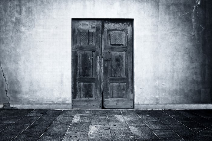 Monochrome photograph of a double wooden door on a textured wall