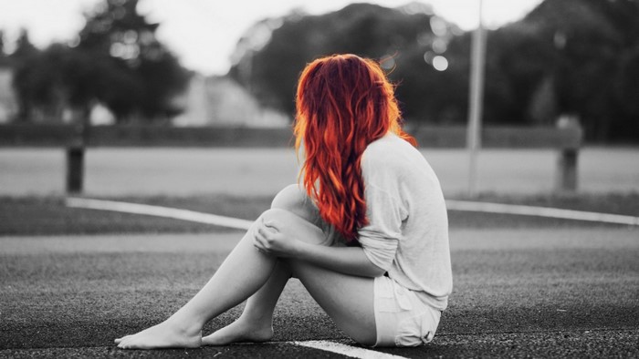 Woman with red hair sitting on the ground