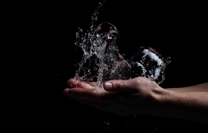 Hands catching water splashes in darkness