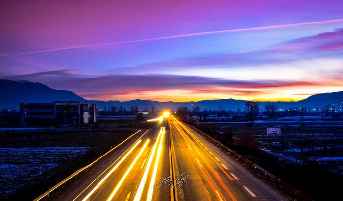 Highway at Dusk with Light Trails and Mountains