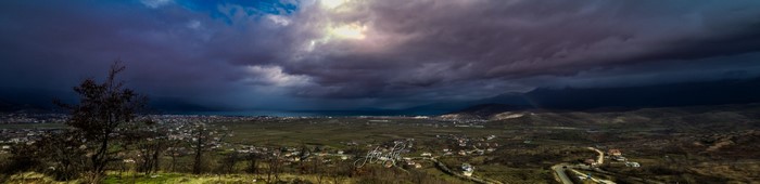 Panoramic view of a stormy sky over a coastal town and hills