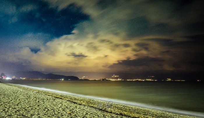 Night beach with city lights and clouds