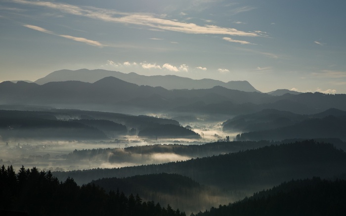 Misty mountain range at sunrise with fog in valleys