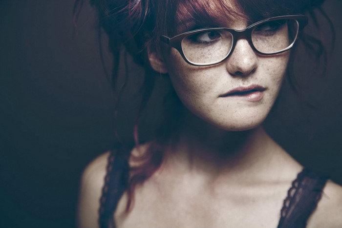 Woman with red hair and glasses biting lip