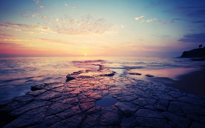 Sunset over the ocean with rocky shore