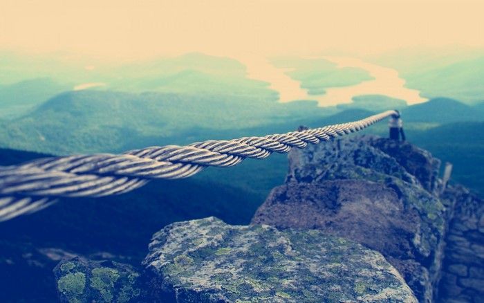 Cable railing on a rocky mountain ridge overlooking a river valley