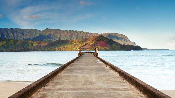 Pier with a covered shelter leading to mountains over the sea