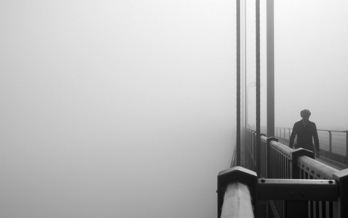 Man walking on a foggy bridge