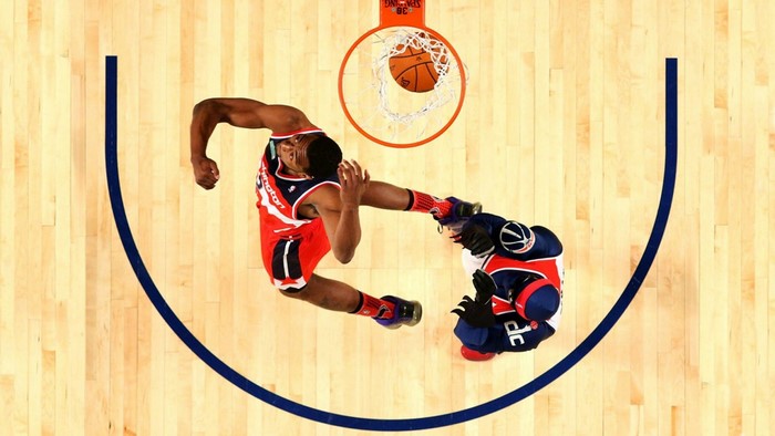 Basketball player dunking over opponent