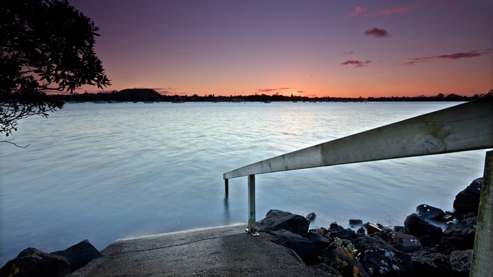 Wooden stairs leading into the water at sunset