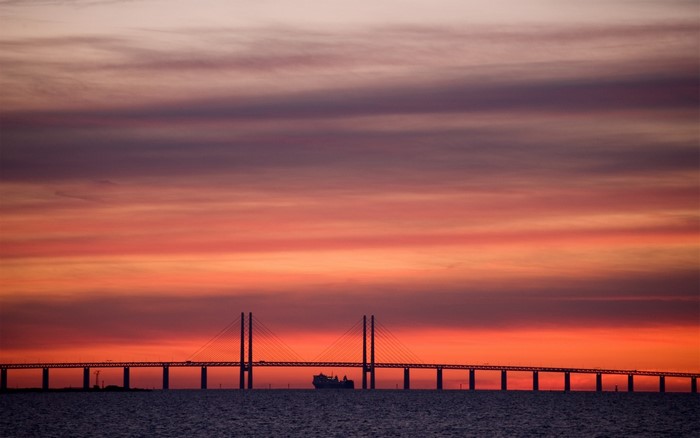 Bridge over water at sunset with ship silhouette