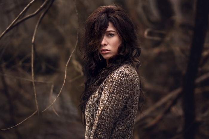 Woman with long brown hair wearing a sweater outdoors