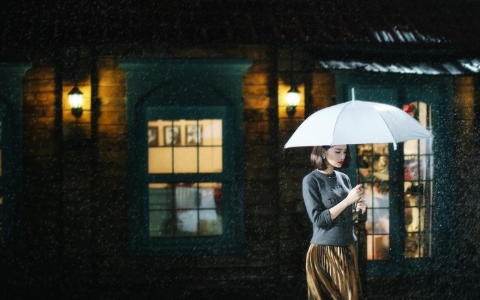 Woman holding umbrella at night in the rain