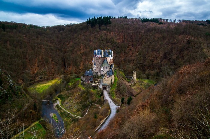 Eltz Castle in a forested valley with a river