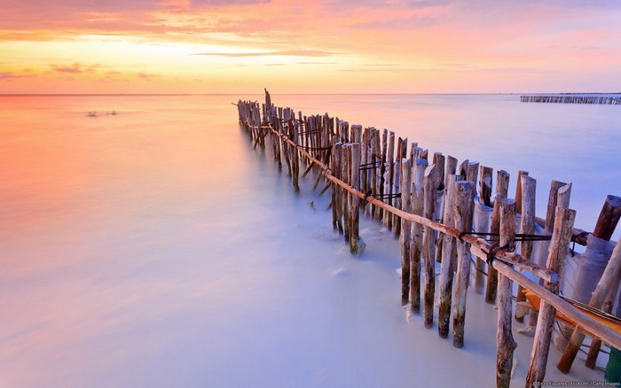 Wooden fence on a calm sea at sunset