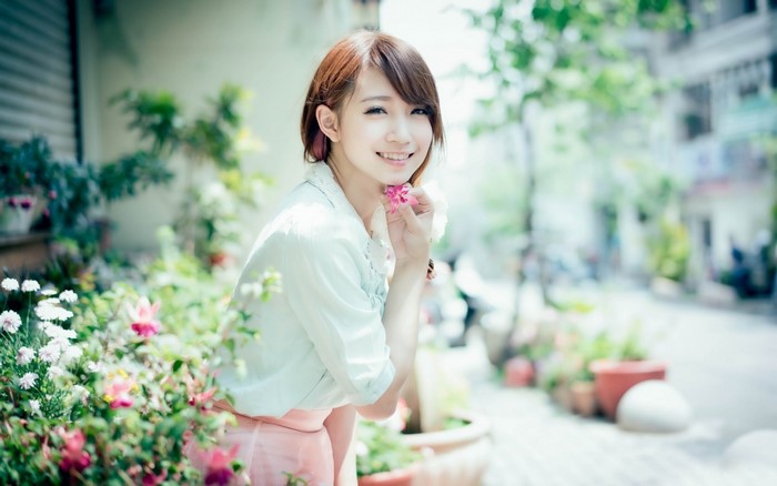 Asian woman holding a pink flower in a garden